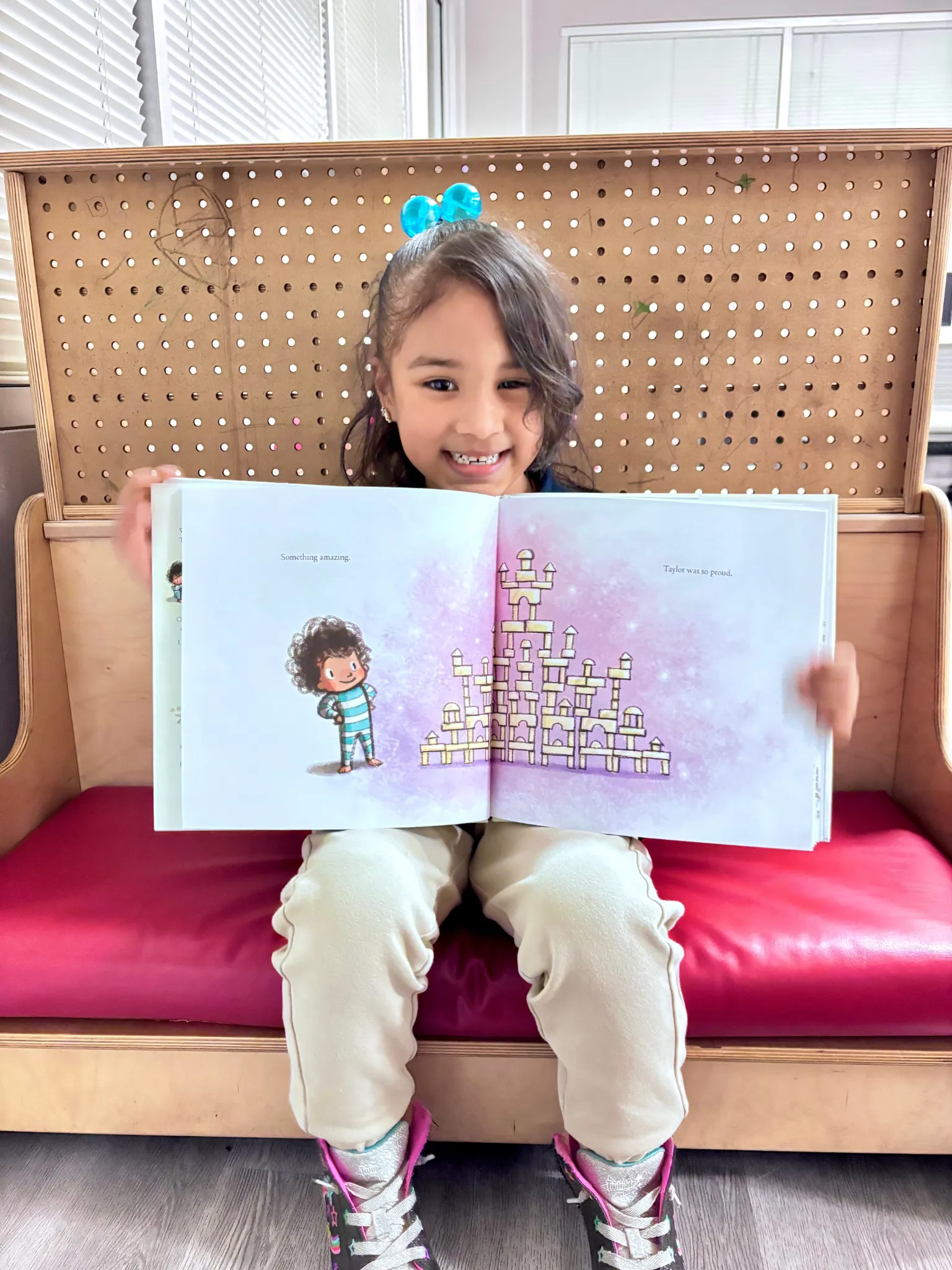 A KidsWay student smiling proudly while reading a picture book