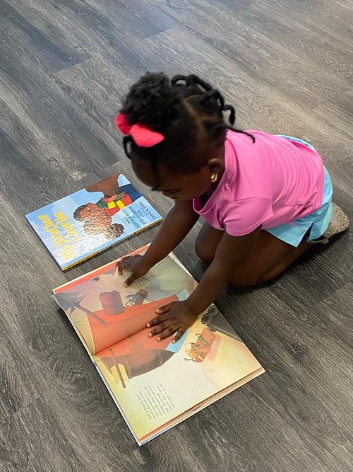 A student reading a picture book on the classroom floor